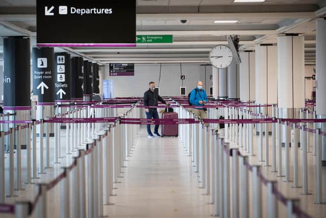 Passengers, wearing a protective face masks, wait at the check-in area at Edinburgh Airport
