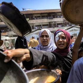 Children queue with pots to receive meals from a charity kitchen in Gaza City yesterday (Picture: Bashar Taleb/AFP via Getty Images)