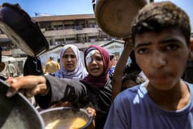 Children queue with pots to receive meals from a charity kitchen in Gaza City yesterday (Picture: Bashar Taleb/AFP via Getty Images)