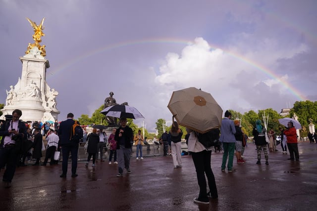 A rainbow is seen over the Queen Victoria Memorial as members of the public gather outside Buckingham Palace in central London.
