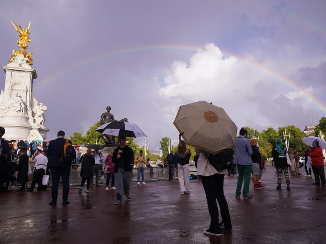 A rainbow is seen over the Queen Victoria Memorial as members of the public gather outside Buckingham Palace in central London.