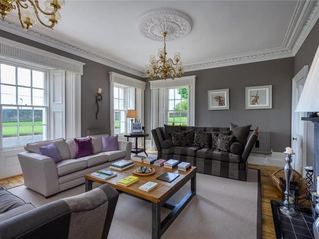 Drawing room with decorative cornice and ceiling roses, fireplace with black marble mantel and solid fuel stove.
