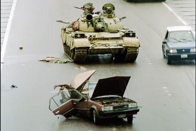 A convoy of Allied armoured vehicles equipped with French-made Crotale anti-aircraft missiles passes an abandoned Iraqi Russian-made T-55 tank in February 1991 on a downtown of Kuwait City after the Allied troops liberated the capital of Kuwait.