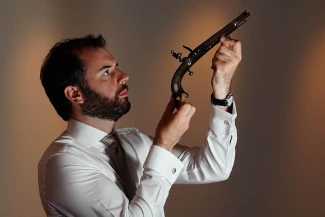 Colin Fraser of Lyon & Turnbull examines the pistol made for Sir Walter Scott and his family. (Picture Credit: Stewart Attwood)