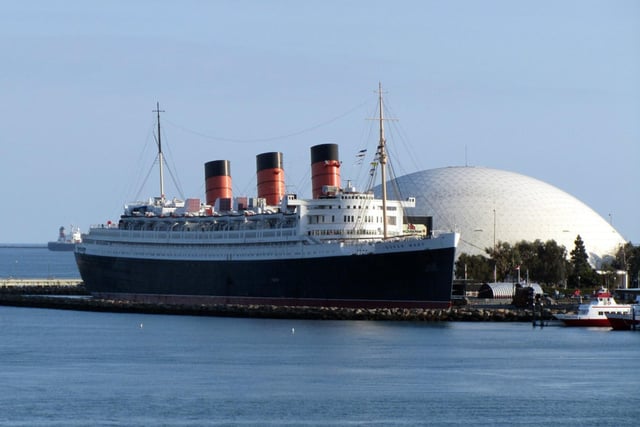 The Queen Mary, along with her sister ship Queen Elizabeth, were built for Cunard’s weekly express service between Southampton, Cherbourg, and New York. It was the dying days of the superliner era which would soon be ended by the growing popularity of transatlantic flights. Built at John Brown’s Clydebank yard and launched in 1934, the Queen Mary won the Blue Ribband in August 1936 for the fastest Atlantic crossing. She regained it in 1938 and would hold the title until 1952. The ship was named after Queen Mary, consort of King George V, and remained popular with passengers and the wider public into the 1960s. She was retired in 1967 and sailed to Long Beach, California, where she is now permanently moored as a floating hotel.