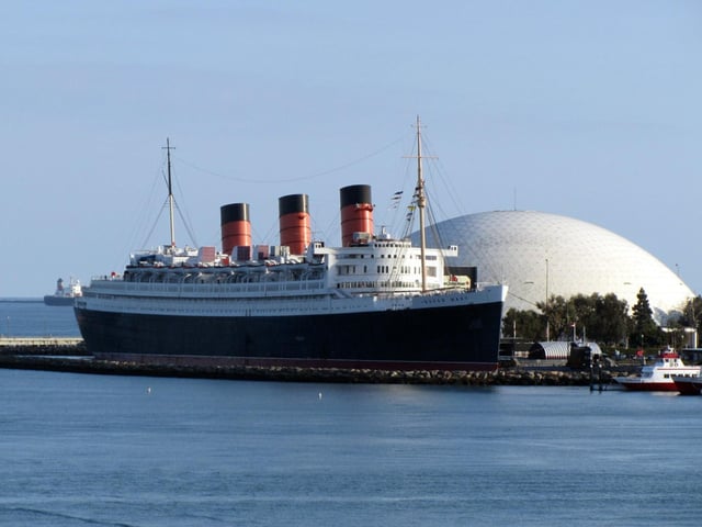 The Queen Mary, along with her sister ship Queen Elizabeth, were built for Cunard’s weekly express service between Southampton, Cherbourg, and New York. It was the dying days of the superliner era which would soon be ended by the growing popularity of transatlantic flights. Built at John Brown’s Clydebank yard and launched in 1934, the Queen Mary won the Blue Ribband in August 1936 for the fastest Atlantic crossing. She regained it in 1938 and would hold the title until 1952. The ship was named after Queen Mary, consort of King George V, and remained popular with passengers and the wider public into the 1960s. She was retired in 1967 and sailed to Long Beach, California, where she is now permanently moored as a floating hotel.