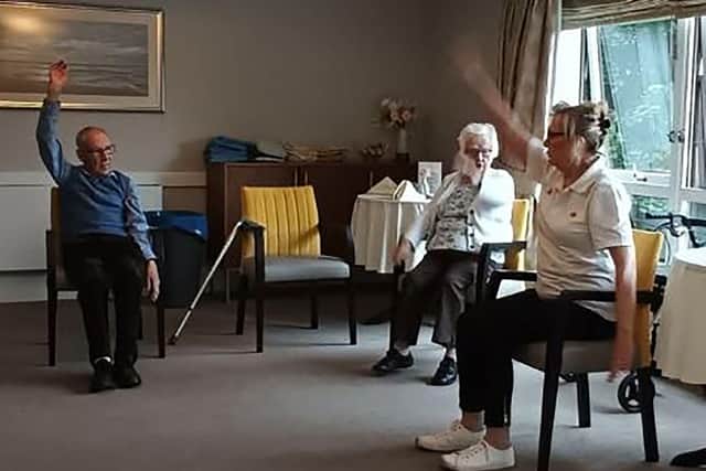 Margaret Finch, Wellbeing Coordinator at HC-One Scotland’s Murrayfield House Care Home hosting daily morning exercise class with residents Douglas and Mary