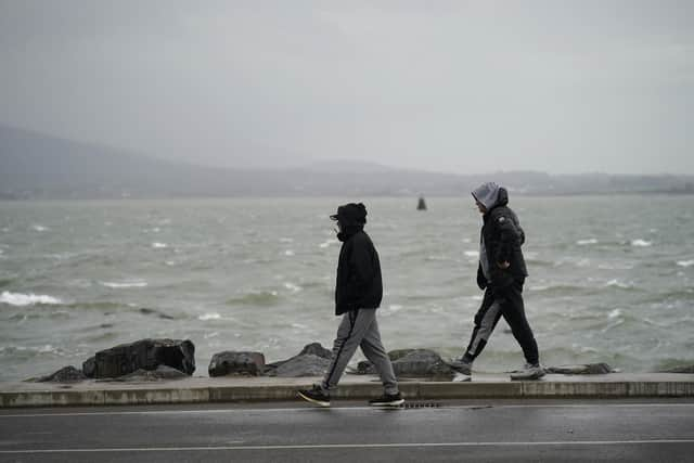 People walk along the seafront as Storm Babet will bring heavy rain to the UK this week, with extensive flooding expected in already-saturated parts of Scotland. Picture: Niall Carson/PA Wire