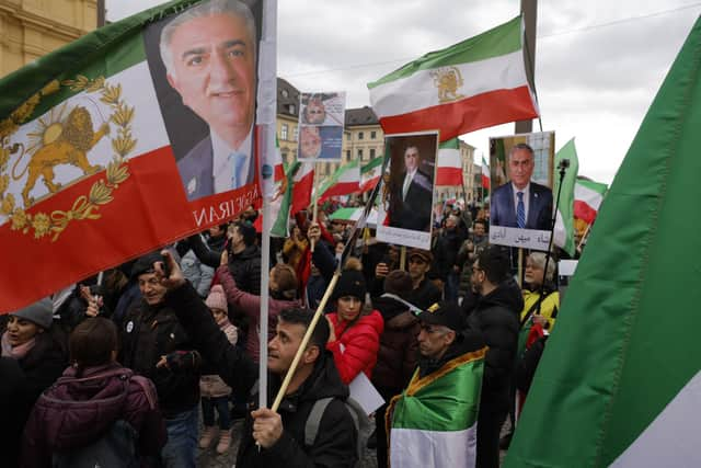 Demonstrators carry historic flags of Iran and portraits of Reza Pahlavi, the oldest son of the last Shah of Iran, during a rally outside the Munich Security Conference (Picture:Odd Andersen/AFP via Getty Images)