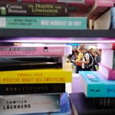 Visitors are seen behind a pile of books on display at the booth of the Random House publishing house at the Leipziger Buchmesse book fair in Leipzig. Picture: SEBASTIAN WILLNOW/dpa/AFP via Getty Images