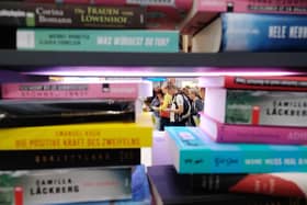 Visitors are seen behind a pile of books on display at the booth of the Random House publishing house at the Leipziger Buchmesse book fair in Leipzig. Picture: SEBASTIAN WILLNOW/dpa/AFP via Getty Images