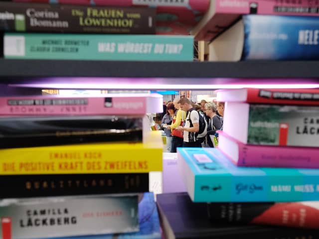 Visitors are seen behind a pile of books on display at the booth of the Random House publishing house at the Leipziger Buchmesse book fair in Leipzig. Picture: SEBASTIAN WILLNOW/dpa/AFP via Getty Images