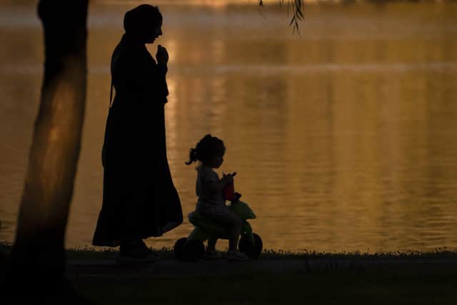 A woman watches over a baby riding a tricycle before sunset by a lake in Bucharest, Romania. Weather services issued a heat warning for the coming week in southern Romania, with temperatures exceeding 40C in the shade. Picture: AP Photo/Andreea Alexandru