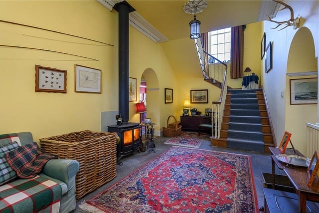 Entrance hall with traditional flagstone flooring, decorative ceiling plasterwork, and a fitted log burner.