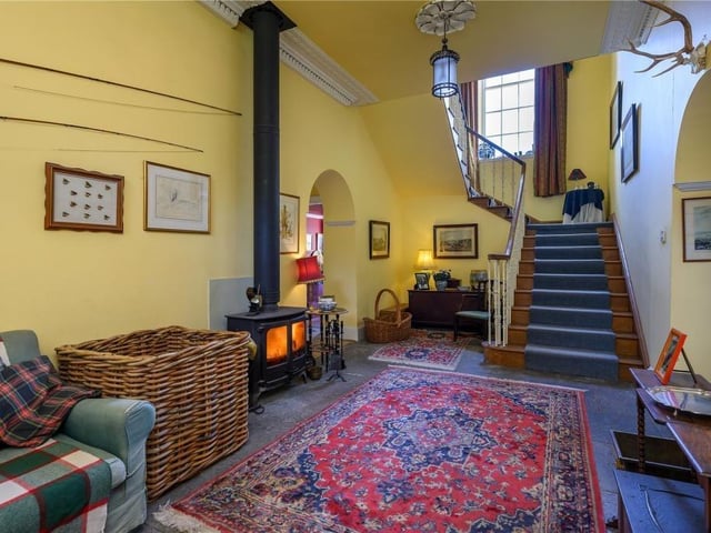 Entrance hall with traditional flagstone flooring, decorative ceiling plasterwork, and a fitted log burner.