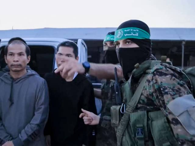 An image from a handout video released by the Hamas Media Office showing members of its Al-Qassam Brigades leading hostages over to officials from the International Committee of the Red Cross in Gaza on Friday. Picture: Hamas Media Office/AFP via Getty Images