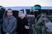 An image from a handout video released by the Hamas Media Office showing members of its Al-Qassam Brigades leading hostages over to officials from the International Committee of the Red Cross in Gaza on Friday. Picture: Hamas Media Office/AFP via Getty Images