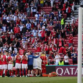 The Denmark players form a shield around their stricken team-mate Christian Eriksen as he receives treatment from medics.