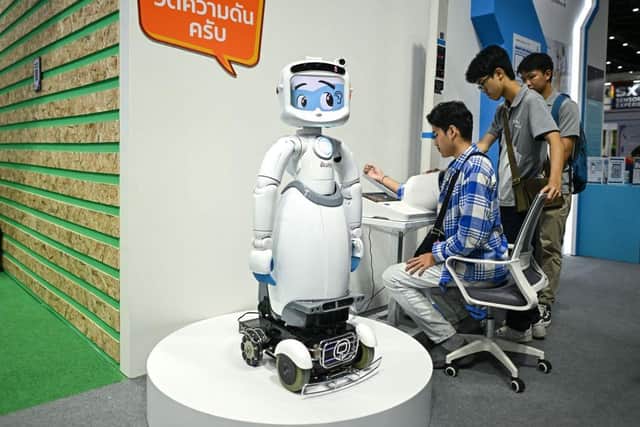 A visitor checks his vitals next to an AI-enabled medical robot at a Bangkok trade show (Picture: Manan Vatsyayana / AFP/ Getty)