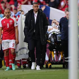 Denmark's players escort midfielder Christian Eriksen as he is evacuated after collapsing on the pitch during the EURO 2020 Group B match between Denmark and Finland.