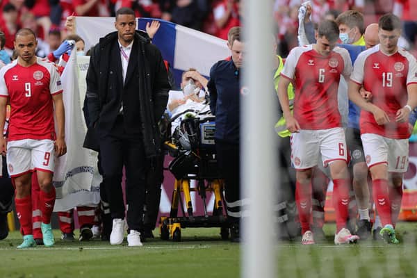Denmark's players escort midfielder Christian Eriksen as he is evacuated after collapsing on the pitch during the EURO 2020 Group B match between Denmark and Finland.