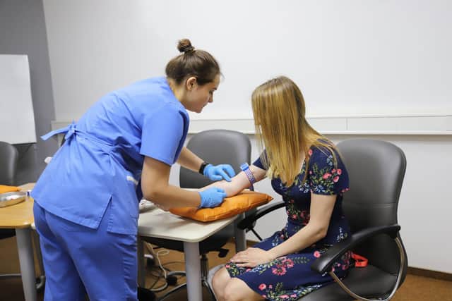A doctor injecting a patient in the arm with a syringe to collect blood. Picture: Getty Images