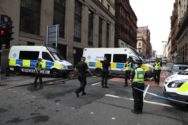 Police close off a road in Glasgow near the scene in West George Street, Glasgow, where a man was shot by an armed officer after another officer was injured during an attack.