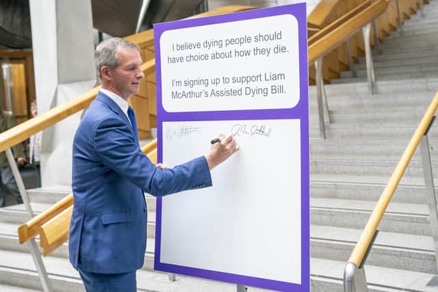 Liam McArthur signs a pledge card in support of his Assisted Dying Bill at the Scottish Parliament