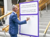 Liam McArthur signs a pledge card in support of his Assisted Dying Bill at the Scottish Parliament