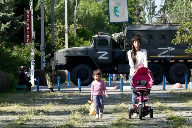A womand and child walking in a park as Russian servicemen patrol  the street in Skadovsk, Kherson Oblast, amid the ongoing Russian military action in Ukraine. Photo Olga MALTSEVA / AFP/ Getty