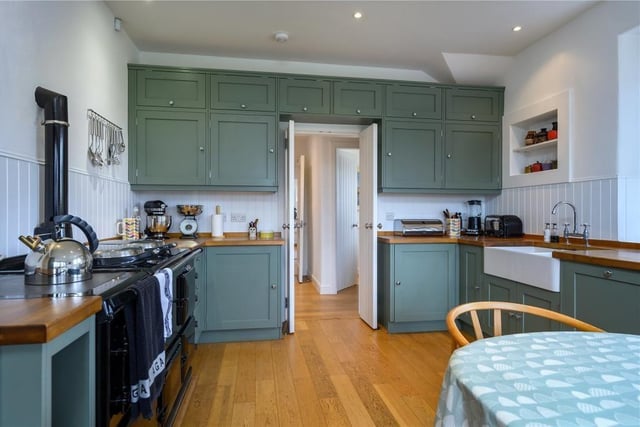 The dining kitchen has painted timber cabinets, timber worktops and a double Belfast sink as well as a four oven AGA and space for a dining table.