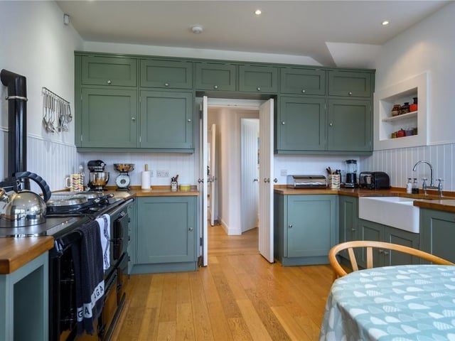 The dining kitchen has painted timber cabinets, timber worktops and a double Belfast sink as well as a four oven AGA and space for a dining table.