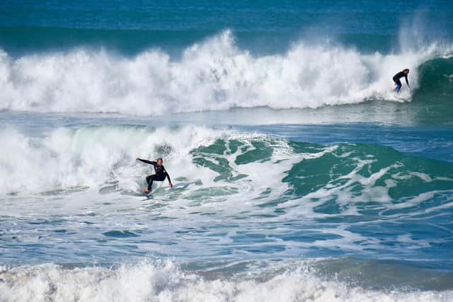 Surfers at Makorori Point. The East Cape has spectacular vistas with sweeping sandy beaches where international surfers ride the huge, crashing waves.