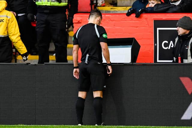 Referee Nick Walsh looks at the monitor during a VAR check at Pittodrie.
