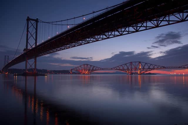 The dawn breaks over the river Forth with the bridges features in the early morning light.