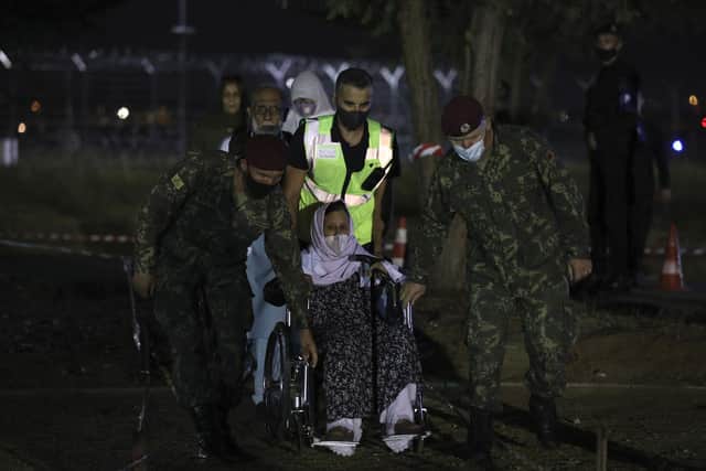 An elderly woman who evacuated from Afghanistan is helped by Albanian soldiers upon her arrival at Tirana International Airport in Tirana, Albania, Friday, Aug 27, 2021. A  (AP Photo/Franc Zhurda)