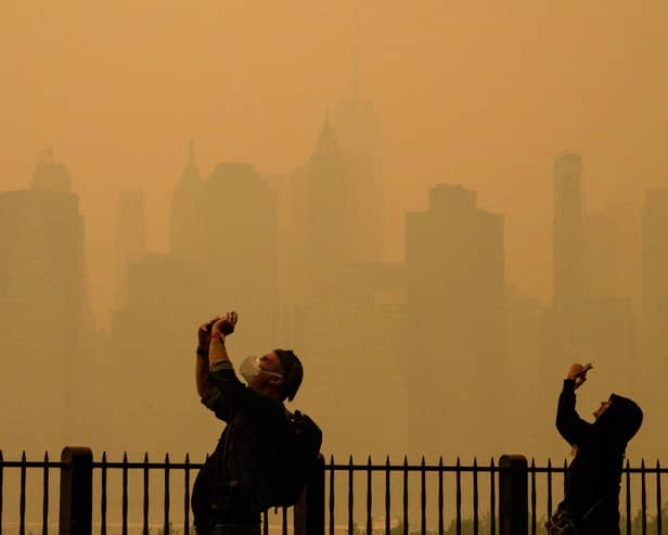 People take photos of the sun as smoke from the wildfires in Canada cause hazy conditions in New York City. Picture: Angela Weiss/AFP via Getty Images