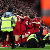 A pitch invader is tackled by stewards after colliding with Andy Robertson of Liverpool as players celebrate after Roberto Firmino's goal against Man Utd.