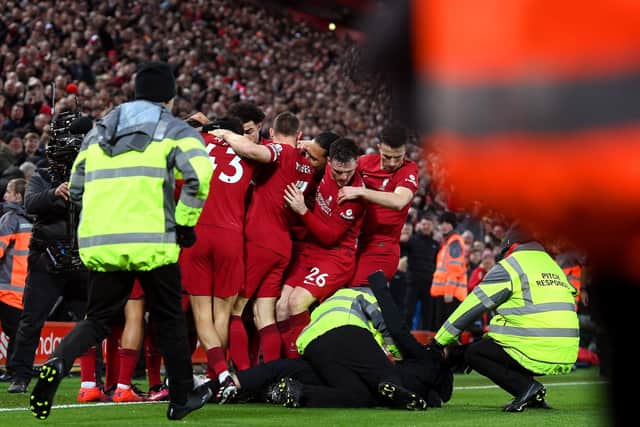 A pitch invader is tackled by stewards after colliding with Andy Robertson of Liverpool as players celebrate after Roberto Firmino's goal against Man Utd.