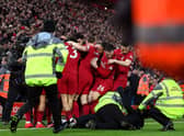 A pitch invader is tackled by stewards after colliding with Andy Robertson of Liverpool as players celebrate after Roberto Firmino's goal against Man Utd.