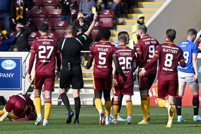 Referee David Dickinson shows a yellow card to Rangers' Leon King for his foul on Motherwell's Stuart McKinstry.