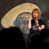 Jay Lafferty performing in front of The Stand Comedy Club's famous cowboy backdrop.