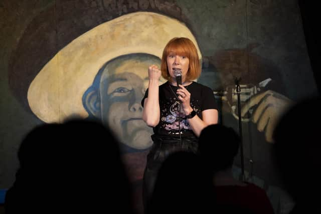 Jay Lafferty performing in front of The Stand Comedy Club's famous cowboy backdrop.