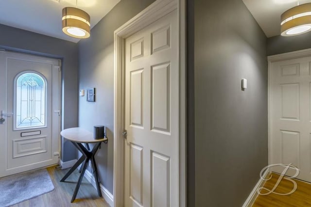 Here is the front door and the pleasant hallway, which leads to all the main rooms in the property. It has laminate flooring and a central heating radiator.