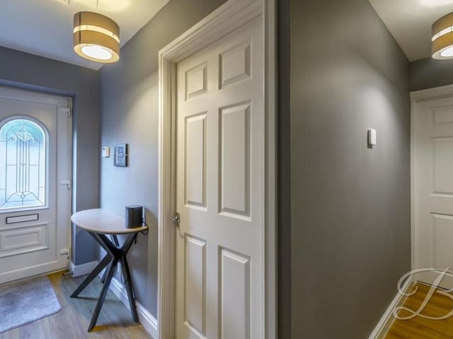 Here is the front door and the pleasant hallway, which leads to all the main rooms in the property. It has laminate flooring and a central heating radiator.