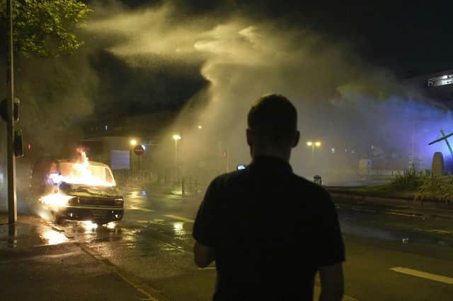 Firefighters use a water hose on a burnt car in Nanterre, outside Paris,