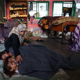 EDITORS NOTE: Graphic content / TOPSHOT - A Palestinian woman covers sleeping children with a blanket as they take refuge in a United nations school, in the Rafah refugee camp, in the southern of Gaza Strip on October 14, 2023, as fighting between Israel and the Hamas movement continues for the eighth consecutive day in the Gaza Strip enclave. Palestinians sought refuge on October 14, 2023, after Israel warned them to evacuate the northern Gaza Strip before an expected ground offensive against Hamas, one week after the deadliest attack in Israel's history. (Photo by MOHAMMED ABED / AFP) (Photo by MOHAMMED ABED/AFP via Getty Images)