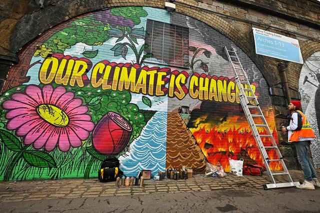 Artists paint a mural on a wall next to the Clydeside Expressway near the Scottish Events Centre which will be hosting the UN's COP26 climate summit (Picture: Jeff J Mitchell/Getty Images)