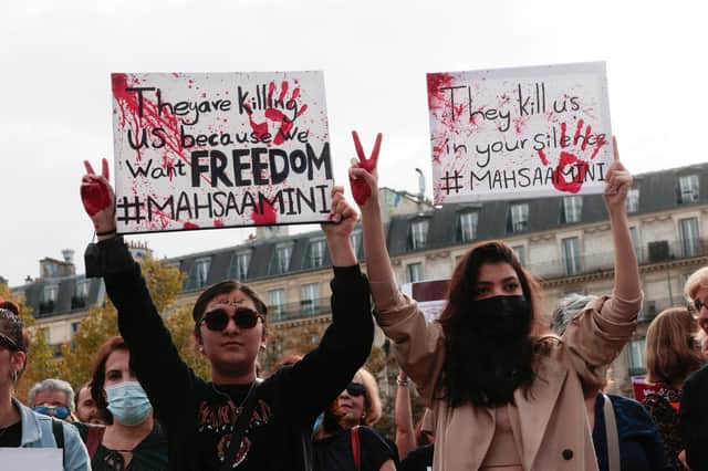 People hold up placards during a rally in Paris last month in support of the anti-government demonstrations in Iran (Picture: Geoffroy van der Hasselt/AFP via Getty Images)