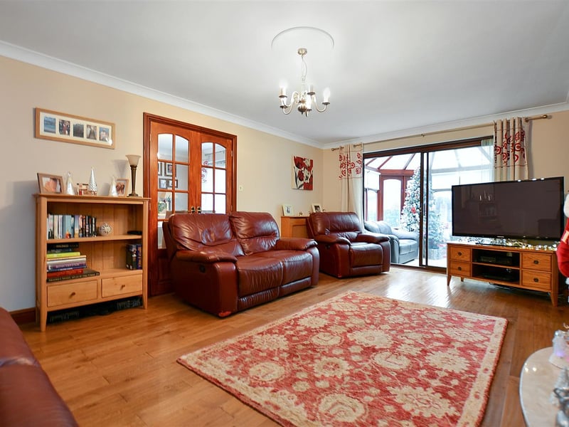 A spacious reception room, with a coal-effect electric fire with marble hearth and traditional-style wood surround, double doors to dining room, and sliding patio door to conservatory.